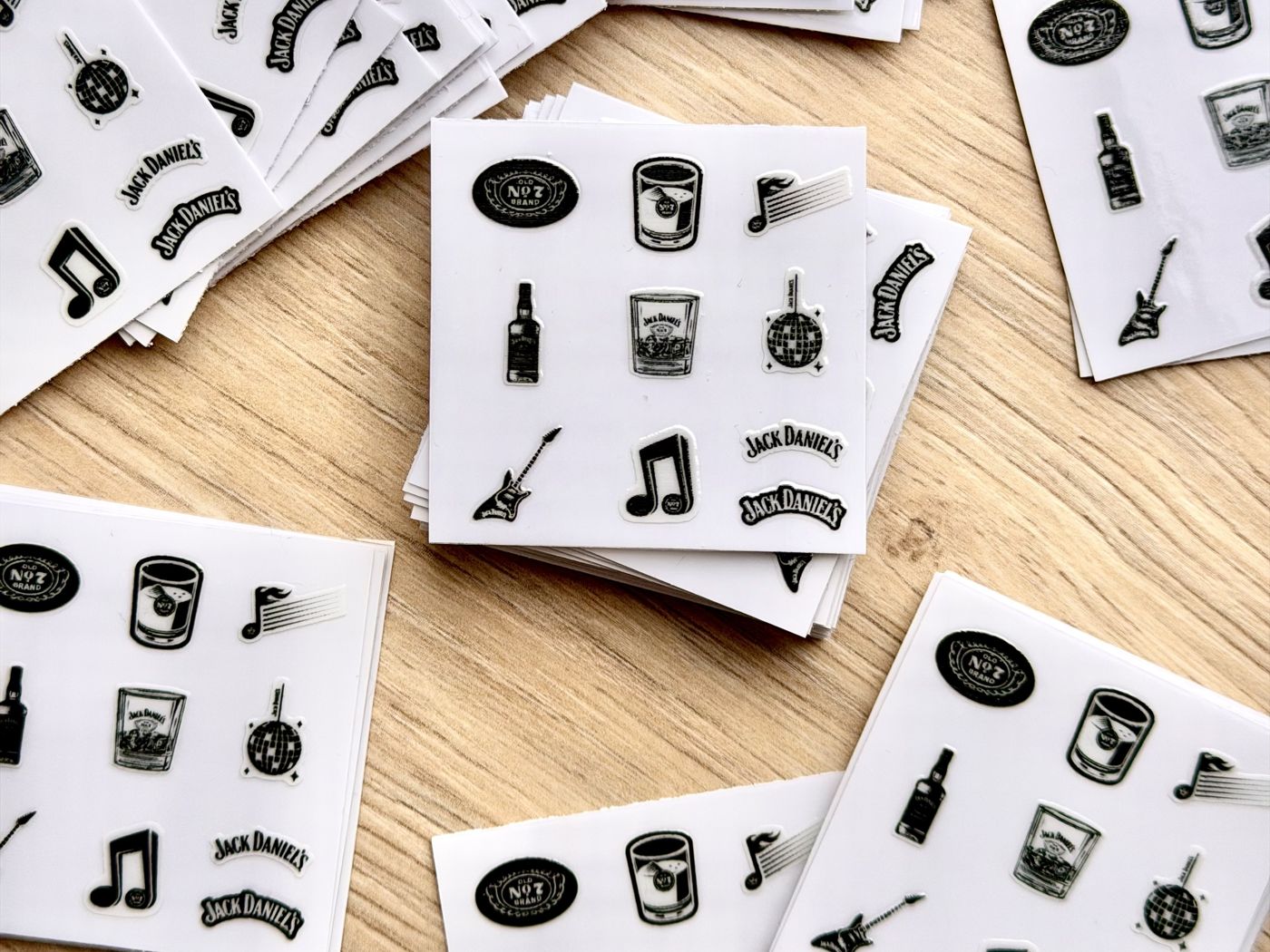 Stapel identischer Nagelsticker-Bögen einer Markenkampagne auf einem Holztisch